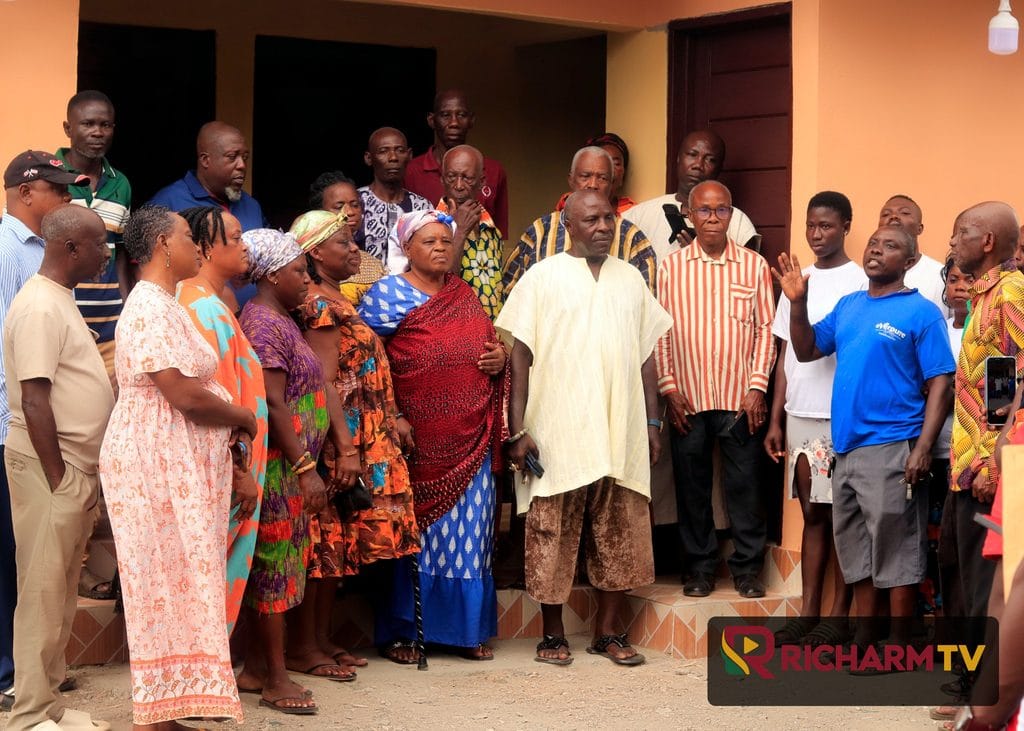 Community members pose for a group photograph outside a building.